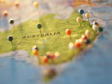 Close-up of a map of Australia with colorful pins marking various cities and destinations.